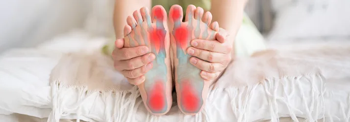 A person holding their feet. Their feet are highlighted red to indicate pain.