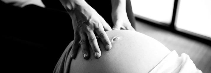 A chiropractor with their hands on a pregnant woman's belly.