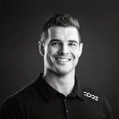 Chiropractor Chad Sheehan smiling. The photo is black and white.