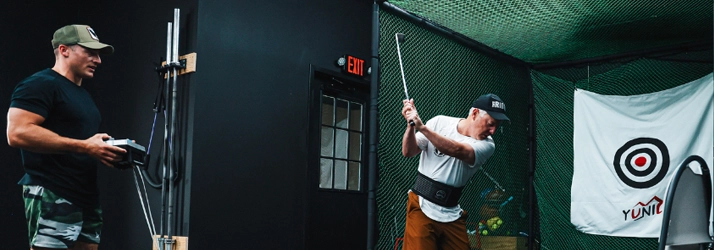 Dr. Chad Teague watching a patient swing a golf club.