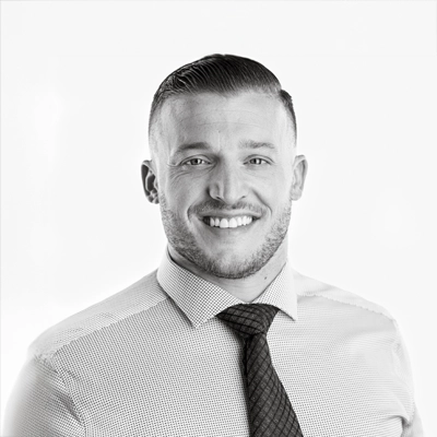 Chiropractor Chad Teague smiling. The photo is black and white.